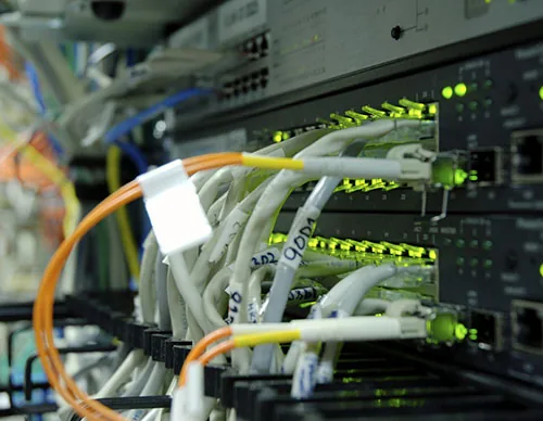 Fiber and copper patch cables connected to a rack of network switches